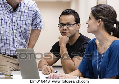 Stock Image - Students working together on laptop. Fotosearch