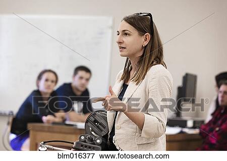 Stock Photo - Teacher talking to students in classroom. Fotosearch