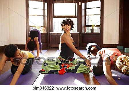 Stock Image - Women practicing yoga in class. Fotosearch