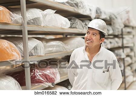 Stock Image - Worker smiling in manufacturing plant. Fotosearch