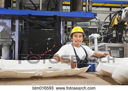 Stock Image - Worker smiling in manufacturing plant. Fotosearch