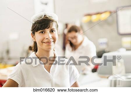 Stock Image - Worker smiling in manufacturing plant. Fotosearch