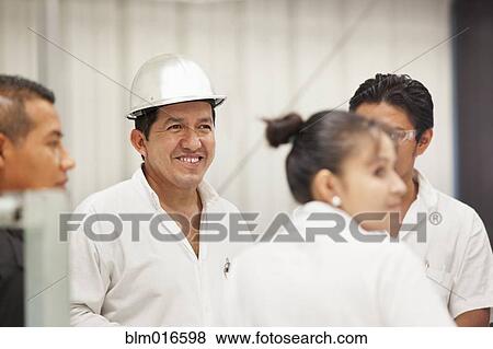 Worker smiling in manufacturing plant View Large Photo Image Stock Photo - Worker smiling in manufacturing plant. Fotosearch