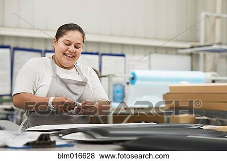Stock Photo - Worker smiling in manufacturing plant. Fotosearch