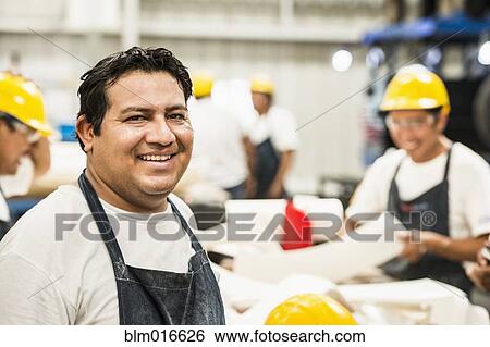 Stock Photograph - Worker smiling in manufacturing plant. Fotosearch