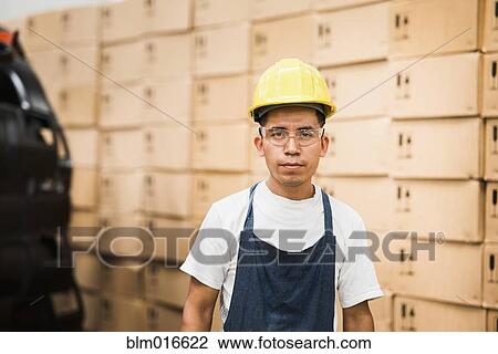 Stock Image - Worker standing in manufacturing plant. Fotosearch