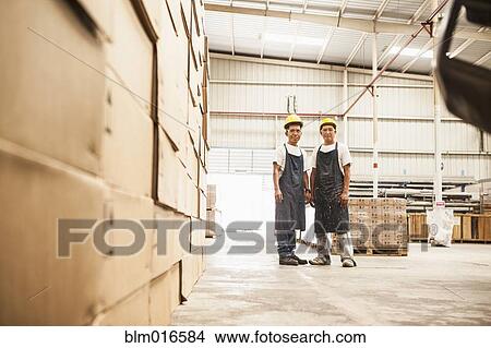 Picture - Workers standing in manufacturing plant. Fotosearch