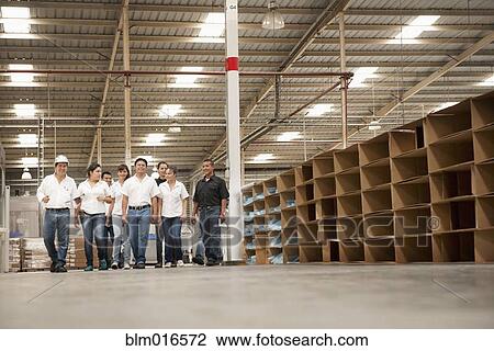 Stock Image - Workers talking in manufacturing plant. Fotosearch