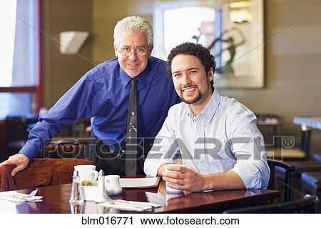 Stock Image - Businessmen smiling together in cafe. Fotosearch