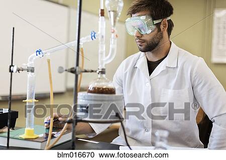 Stock Image - Caucasian student working in chemistry lab. Fotosearch