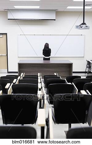Stock Image - Caucasian teacher at whiteboard in empty classroom. Fotosearch