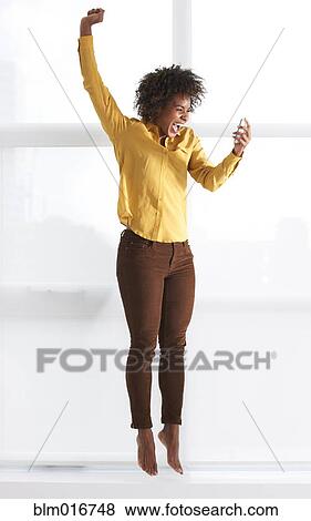 Cheering Black woman using cell phone View Large Photo Image Stock Photo - Cheering Black woman using cell phone. Fotosearch