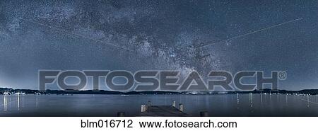 Stock Image - Clouds in night sky over still water. Fotosearch