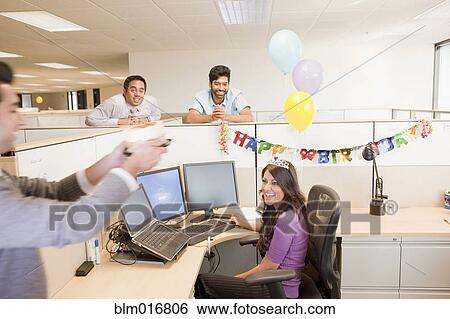 Stock Photograph - Colleagues celebrating birthday in office. Fotosearch