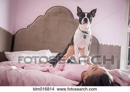 Picture - Girl playing with dog on bed. Fotosearch