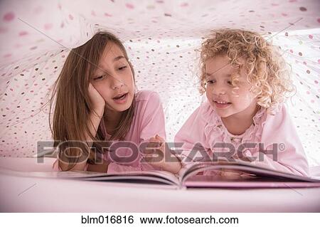 Girls reading book together under blanket View Large Photo Image Stock Photograph - Girls reading book together under blanket. Fotosearch