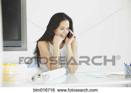 Stock Photograph - Hispanic businesswoman on cell phone in office. Fotosearch