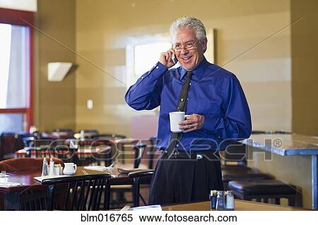 Stock Photography - Hispanic cafe owner talking on cell phone. Fotosearch
