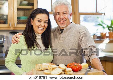 Stock Image - Hispanic couple cooking together in kitchen. Fotosearch