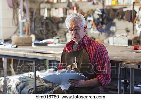 Stock Image - Hispanic craftsman working in shop. Fotosearch