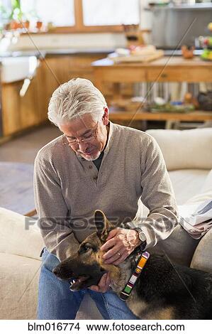 Hispanic man petting dog in living room View Large Photo Image Picture - Hispanic man petting dog in living room. Fotosearch