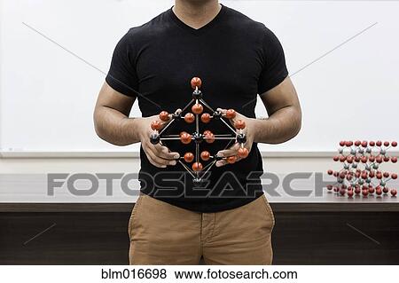 Stock Photo - Hispanic student holding molecular model in classroom. Fotosearch