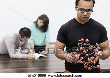 Stock Photo - Hispanic student holding molecular model in classroom. Fotosearch