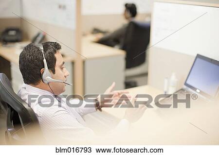 Stock Image - Indian businessman talking on headset. Fotosearch