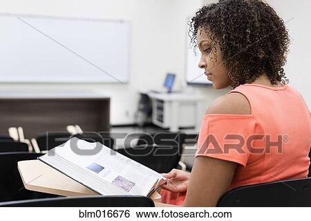 Mixed race student reading in empty classroom View Large Photo Image Stock Photograph - Mixed race student reading in empty classroom. Fotosearch