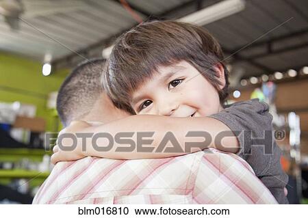 Stock Image - Smiling boy hugging father. Fotosearch