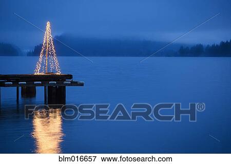 Stock Photo - String of lights in tree shape on wooden pier. Fotosearch