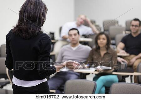 Stock Image - Teacher talking to students in classroom. Fotosearch