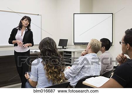 Stock Photo - Teacher talking to students in classroom. Fotosearch