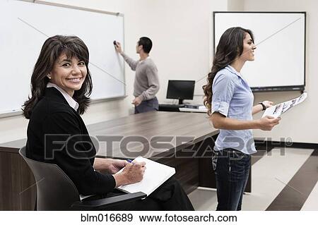 Stock Photo - Teacher watching student present paper to class. Fotosearch