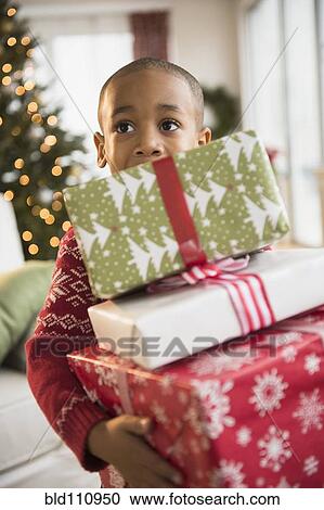 Stock Image - African American boy carrying Christmas presents. Fotosearch
