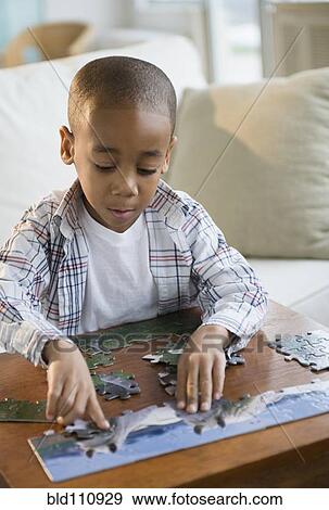 Stock Photo - African American boy playing with jigsaw puzzle. Fotosearch