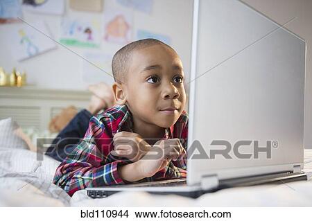 African American boy using laptop on bed View Large Photo Image Picture - African American boy using laptop on bed. Fotosearch