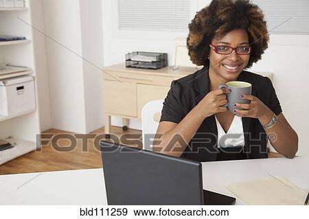 African American businesswoman drinking cup of coffee at desk View Large Photo Image Stock Photo - African American businesswoman drinking cup of coffee at desk. Fotosearch
