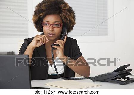 Stock Photo - African American businesswoman working at desk. Fotosearch