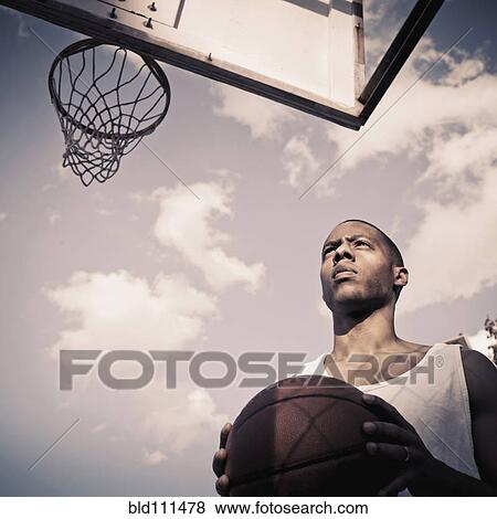Stock Photo - African American man playing basketball on court. Fotosearch
