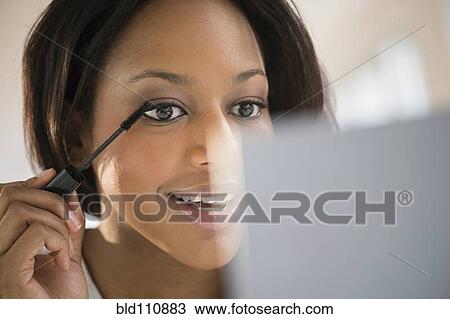 Stock Image - African American woman applying makeup. Fotosearch