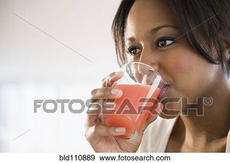 Stock Photo - African American woman drinking glass of juice. Fotosearch