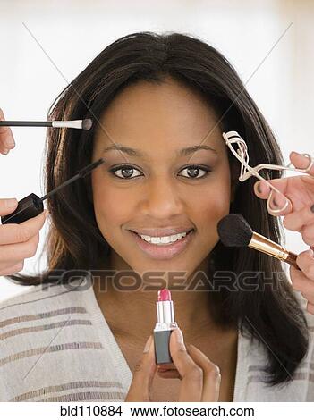 Picture - African American woman having makeup applied. Fotosearch
