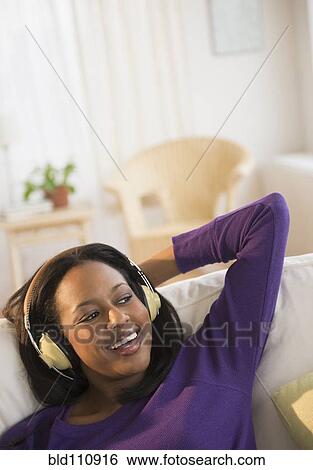African American woman listening to headphones on sofa View Large Photo Image Stock Photograph - African American woman listening to headphones on sofa. Fotosearch