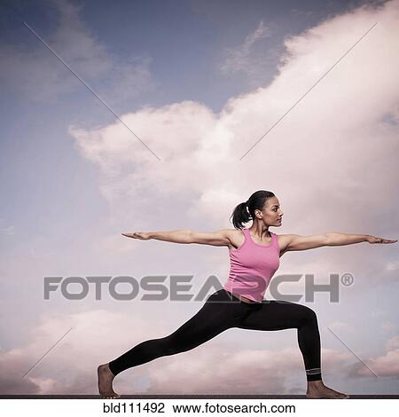 Stock Image - African American woman practicing yoga outdoors. Fotosearch