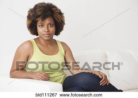 Stock Photo - African American woman sitting on sofa. Fotosearch
