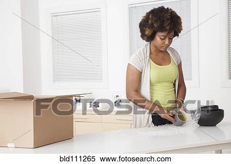 Stock Photography - African American woman unpacking in new home. Fotosearch