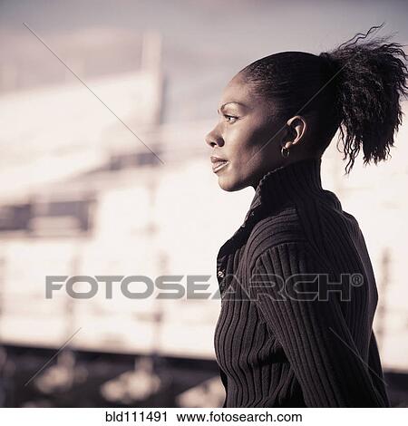 Stock Image - African American woman walking by bleachers. Fotosearch