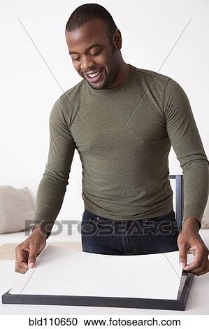 Stock Image - Black man adjusting paper. Fotosearch