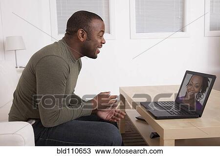 Stock Image - Black man talking to wife on computer. Fotosearch